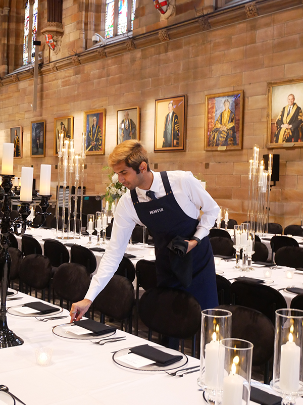 HostCo front-of-house staff setting up tables for SIXDO's dinner event at the University of Sydney's Great Hall